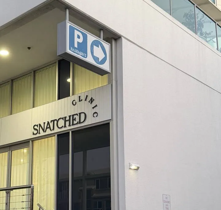Basement parking sign with an arrow, on the corner by Snatched Clinic